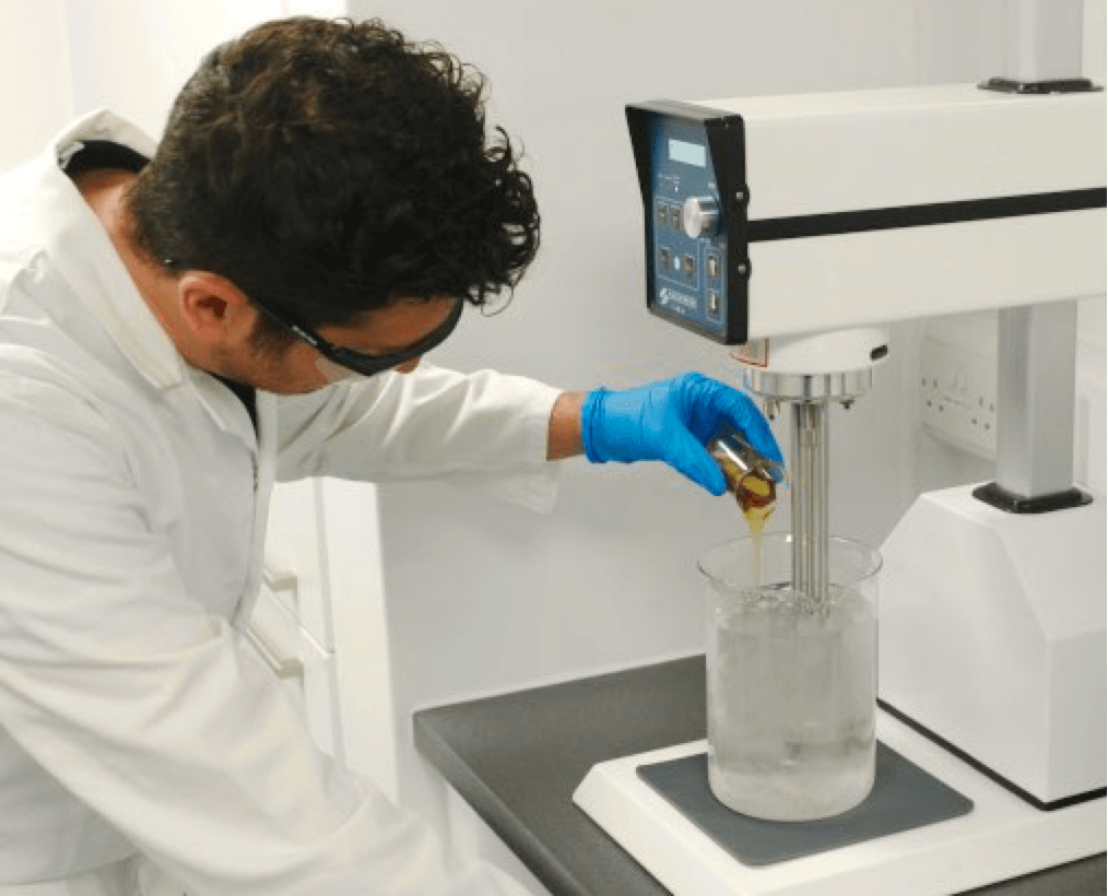 Austin and Kat makes all their own products in their own Makery facility, a person in a lab coat pours oil into a beaker to demonstrate.