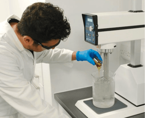 Austin and Kat makes all their own products in their own Makery facility, a person in a lab coat pours oil into a beaker to demonstrate.